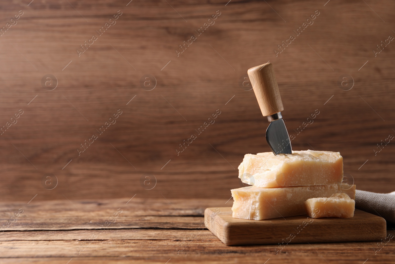 Photo of Delicious parmesan cheese with knife on wooden table. Space for text