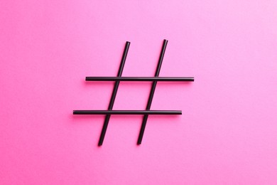 Photo of Hashtag symbol made of drinking straws on pink background, top view