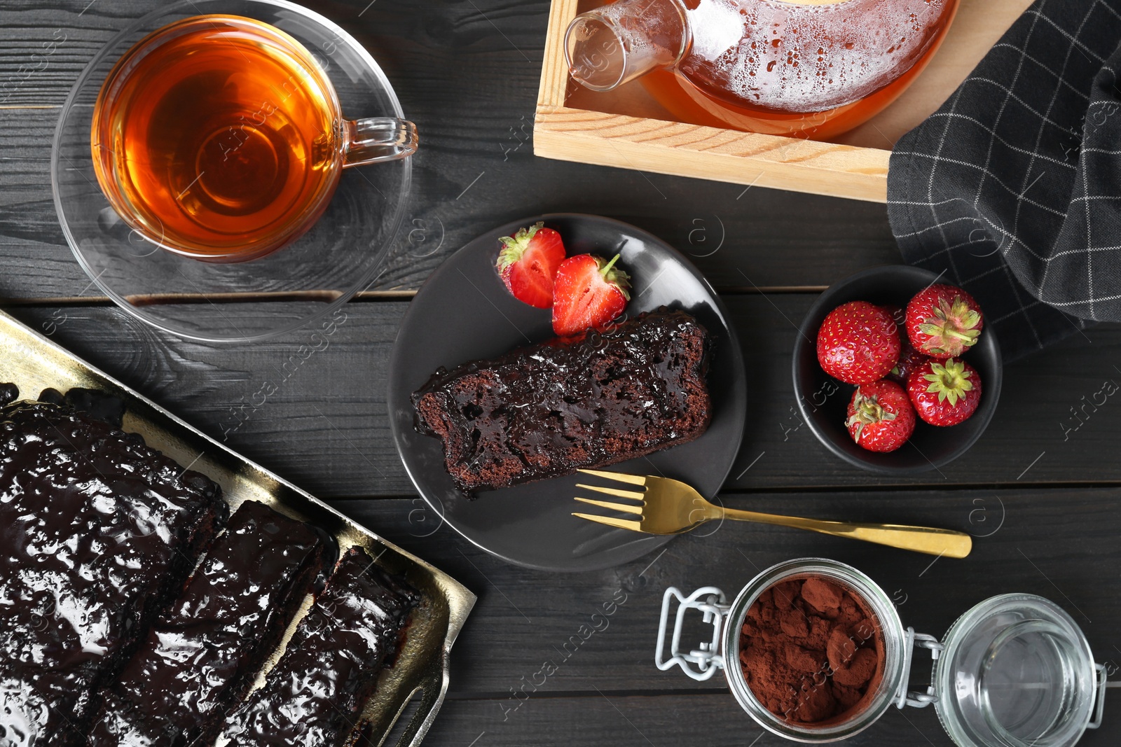 Photo of Tasty chocolate sponge cake served on black wooden table, flat lay