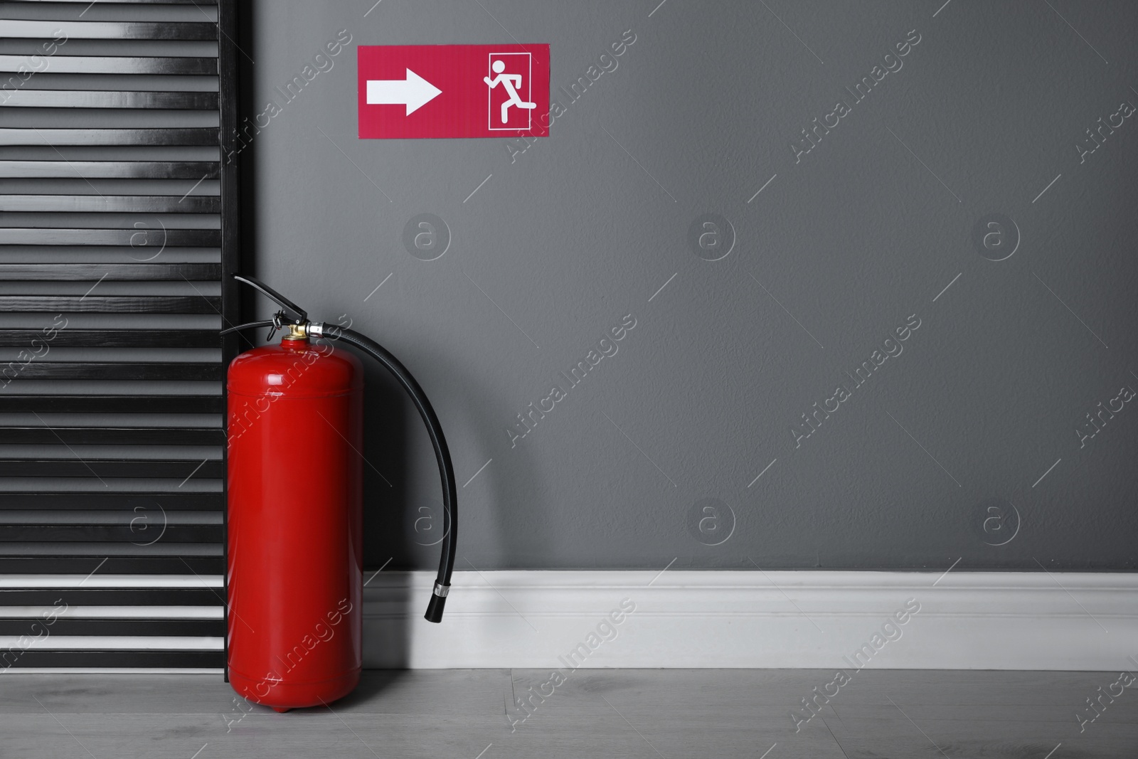 Photo of Fire extinguisher and emergency exit sign indoors. Space for text