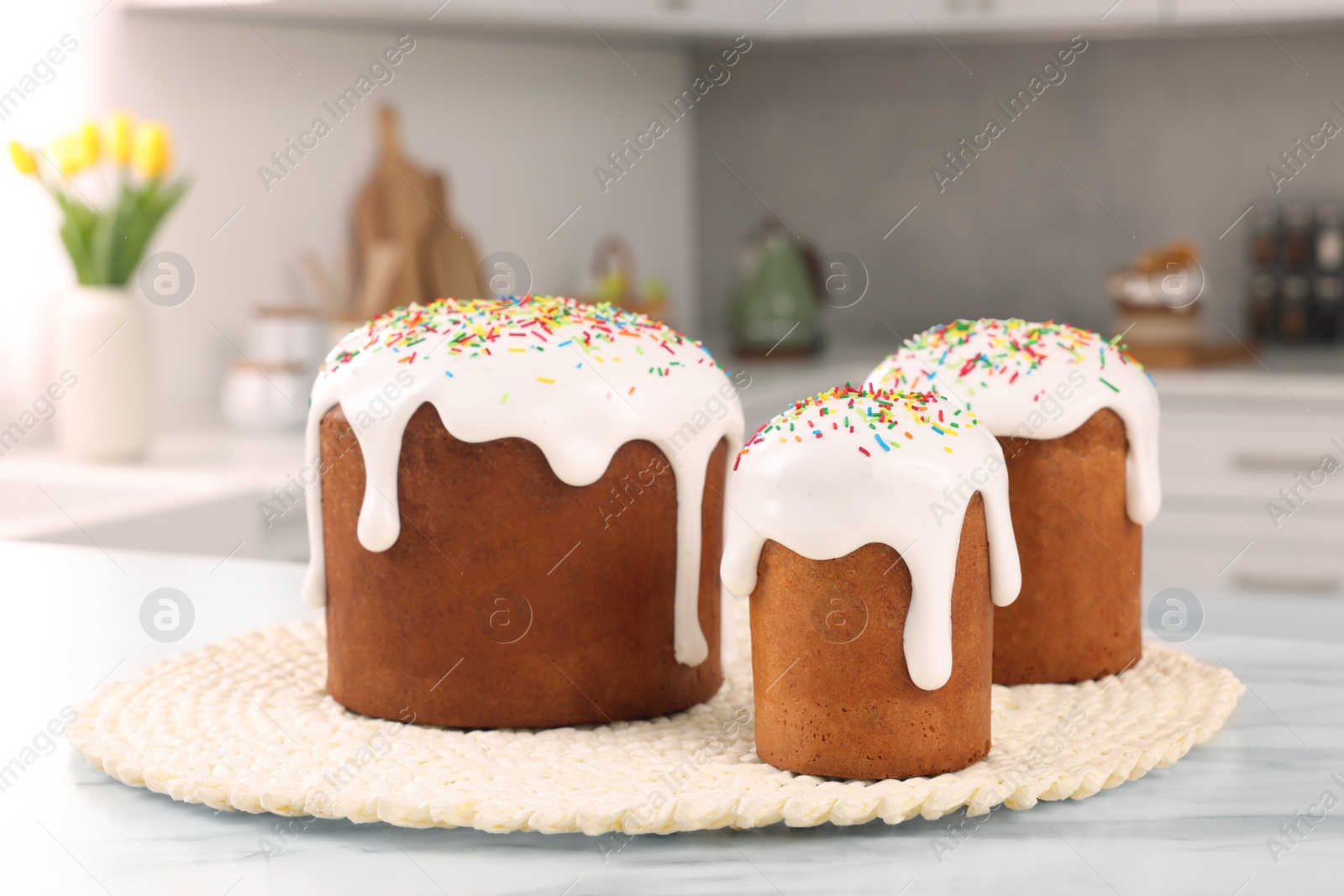 Photo of Delicious Easter cakes with sprinkles on white table in kitchen