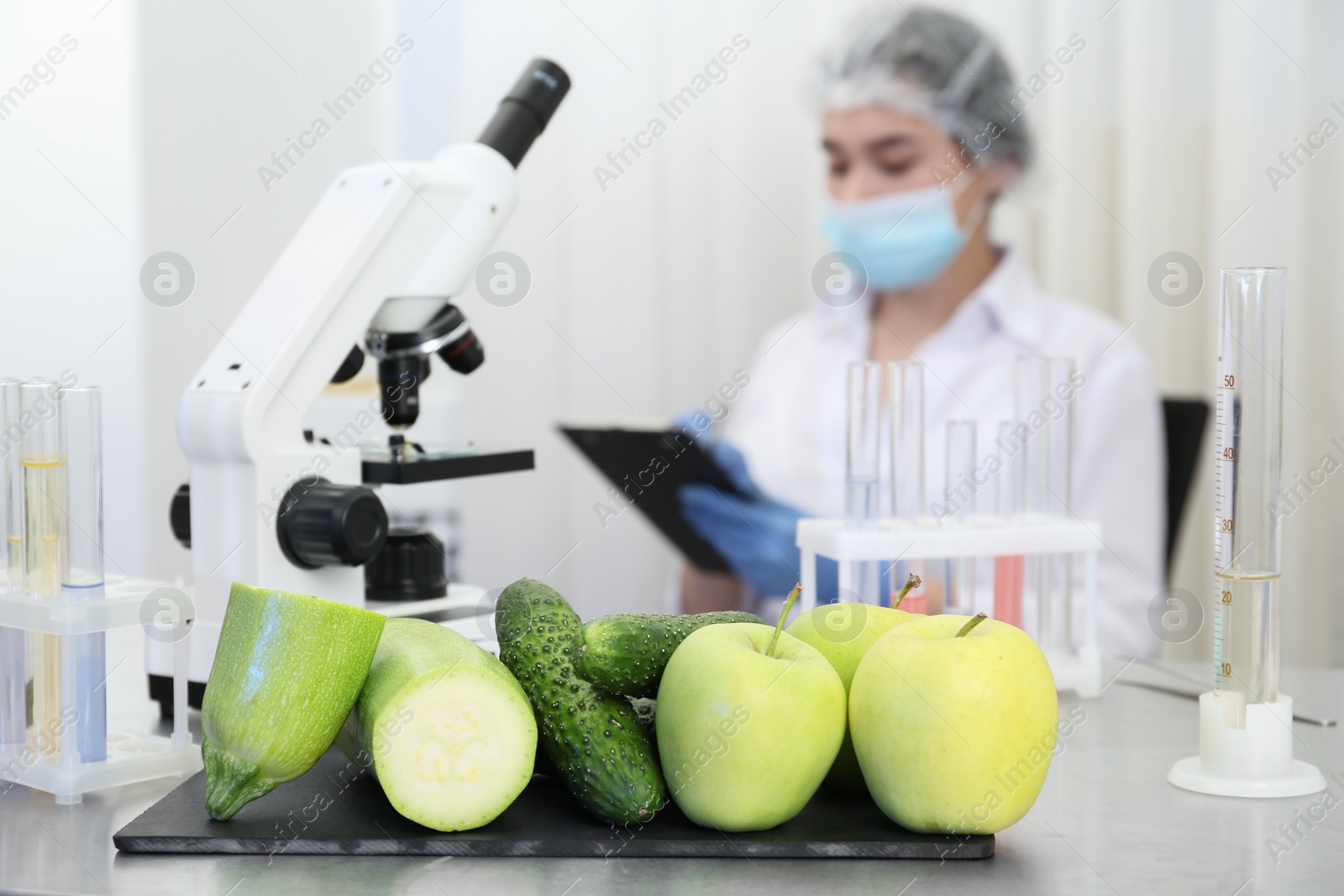 Photo of Fresh vegetables, fruits on table and scientist proceeding quality control in laboratory