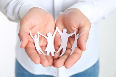 Photo of Young man holding paper family figure, closeup of hands