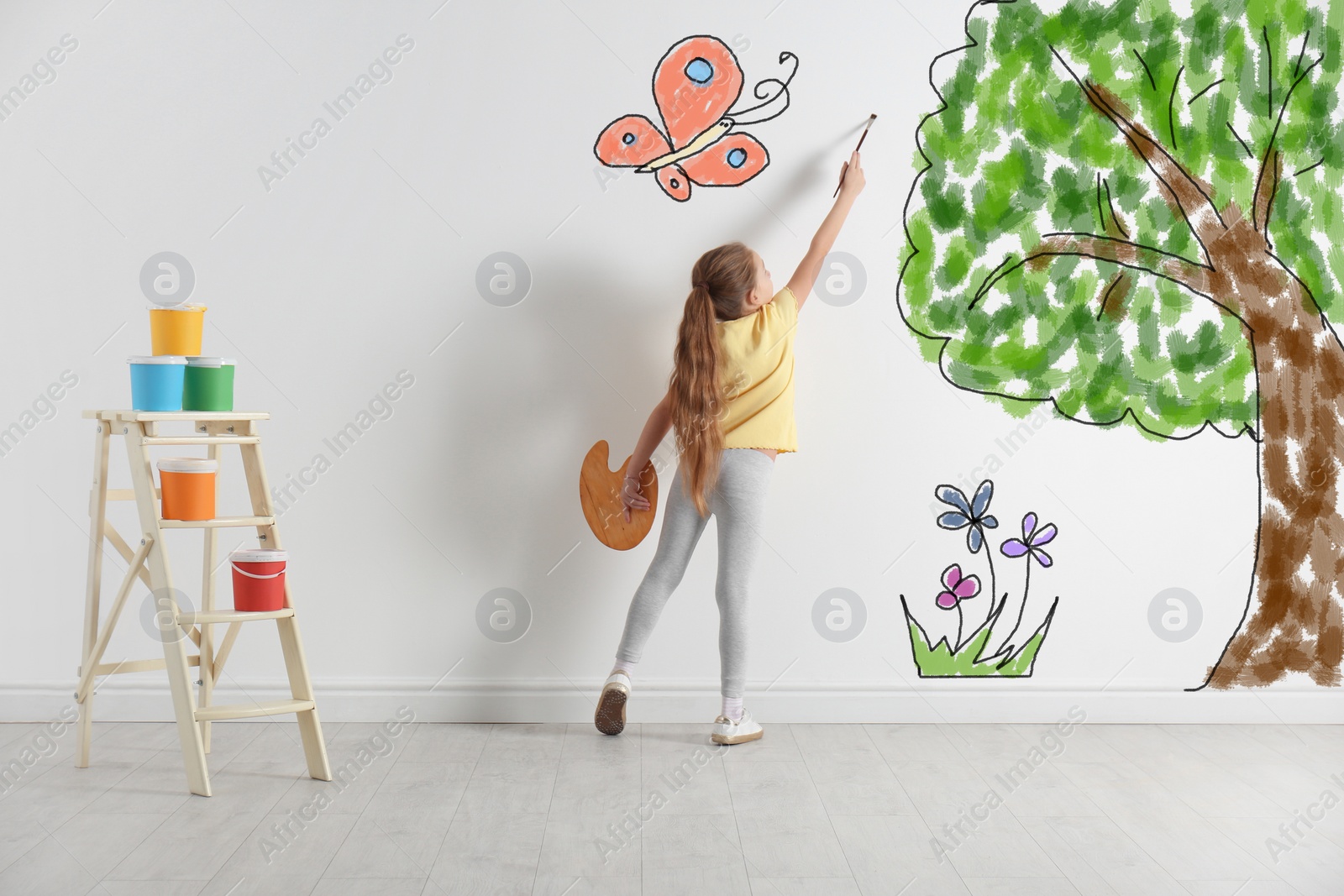 Image of Cute child drawing nature on white wall indoors