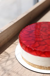 Photo of Delicious cheesecake with jelly and strawberries on wooden table, closeup