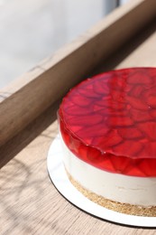 Delicious cheesecake with jelly and strawberries on wooden table, closeup