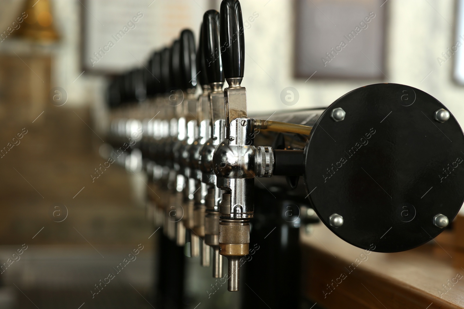 Photo of New modern beer taps in pub, closeup. Professional bar equipment