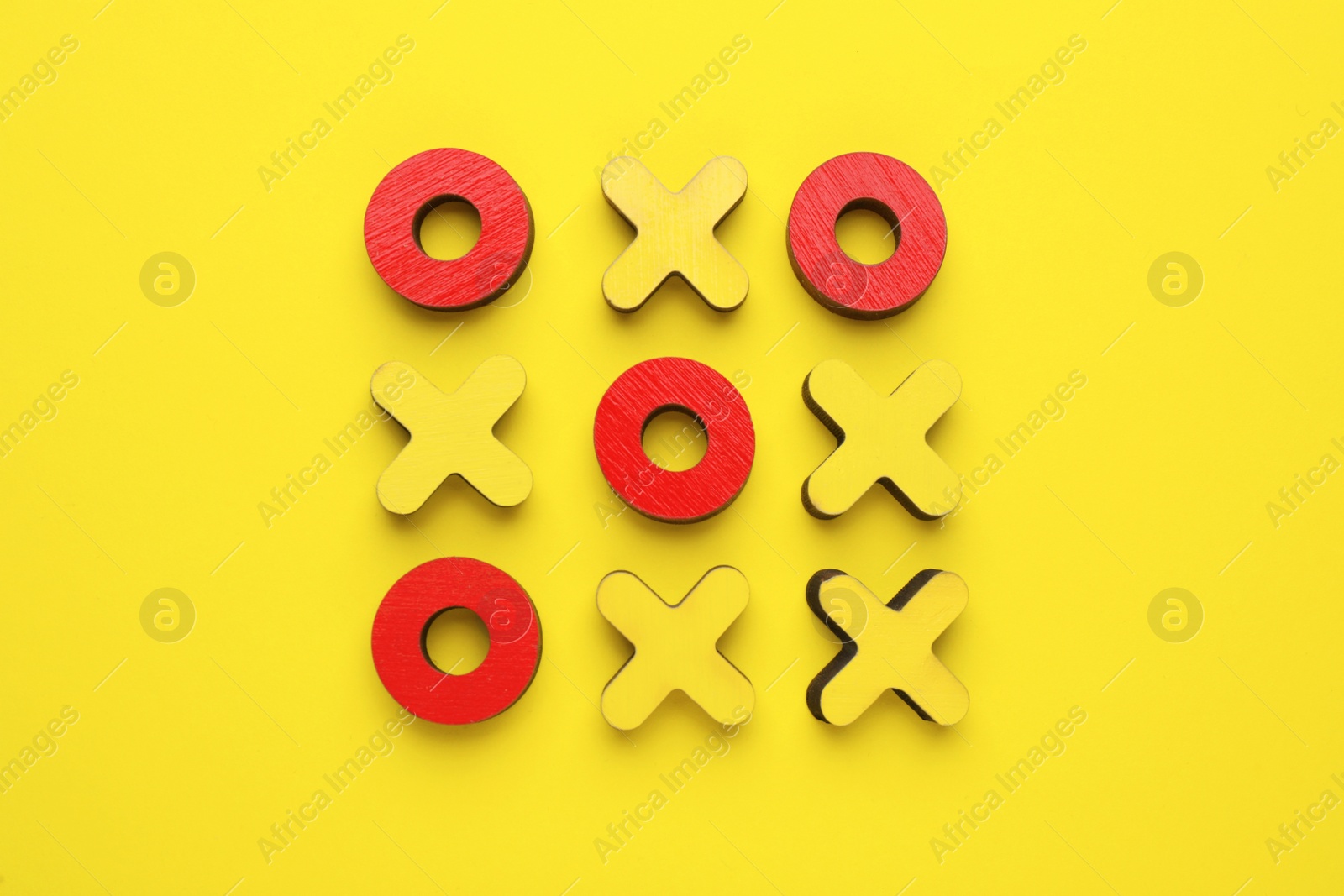 Photo of Wooden tic-tac-toe set on yellow background, flat lay