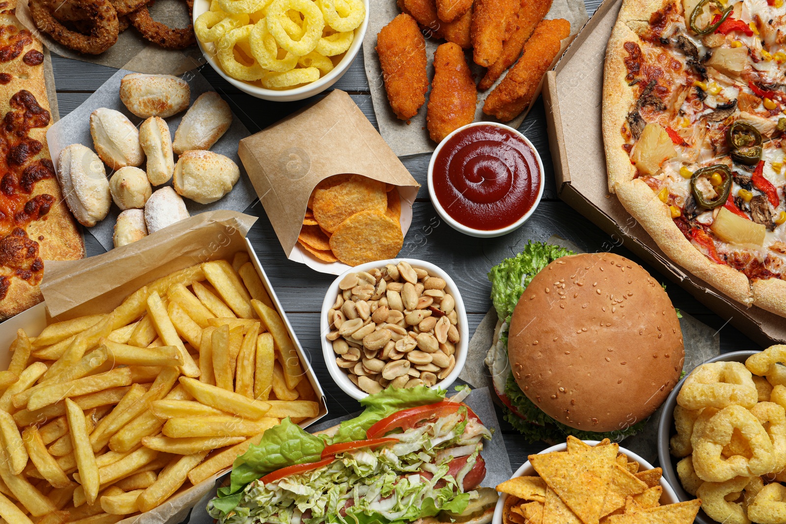 Photo of French fries, chips other fast food on gray wooden table, flat lay