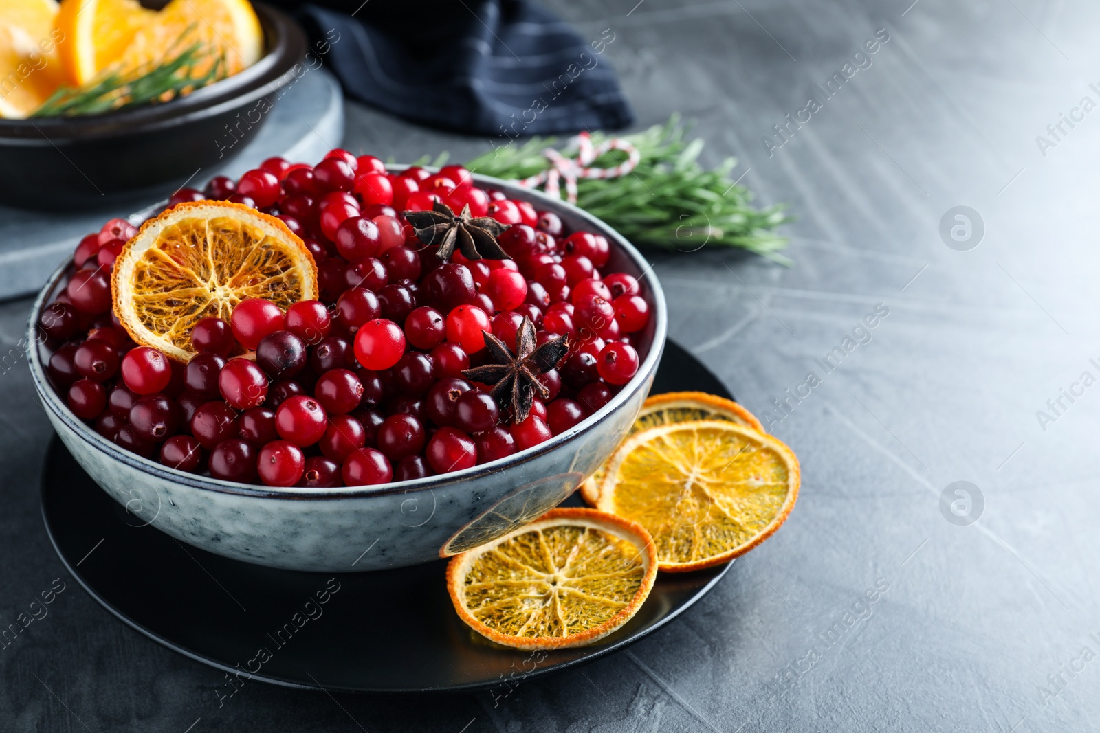 Photo of Fresh ripe cranberries, spices and orange slices on grey table