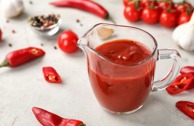 Photo of Jug with spicy chili sauce on light table