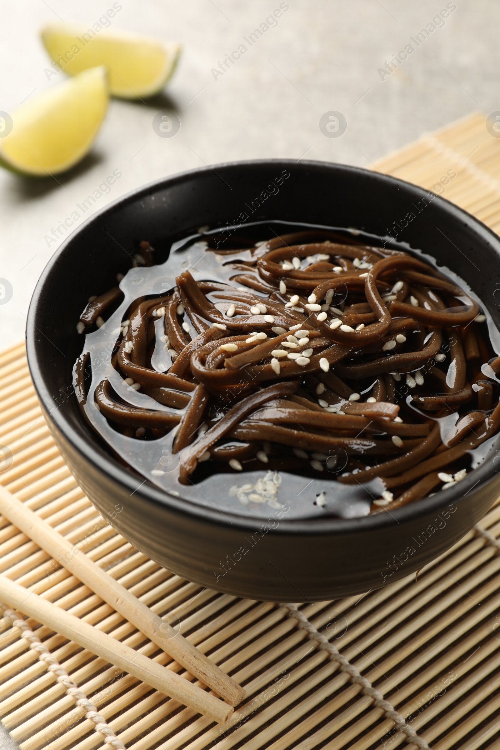 Photo of Tasty buckwheat noodles (soba) with sauce in bowl and chopsticks on table