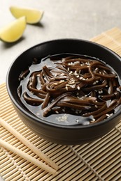 Photo of Tasty buckwheat noodles (soba) with sauce in bowl and chopsticks on table