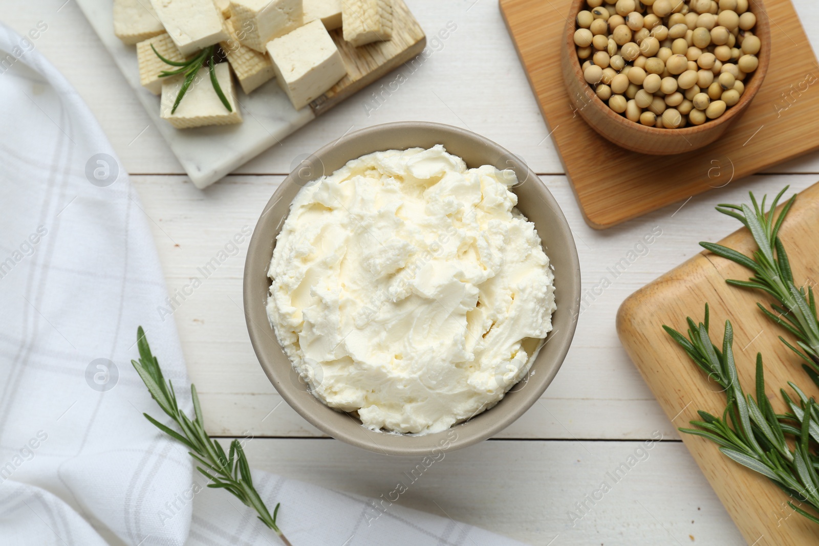 Photo of Delicious tofu cheese, soy beans and rosemary on white wooden table, flat lay