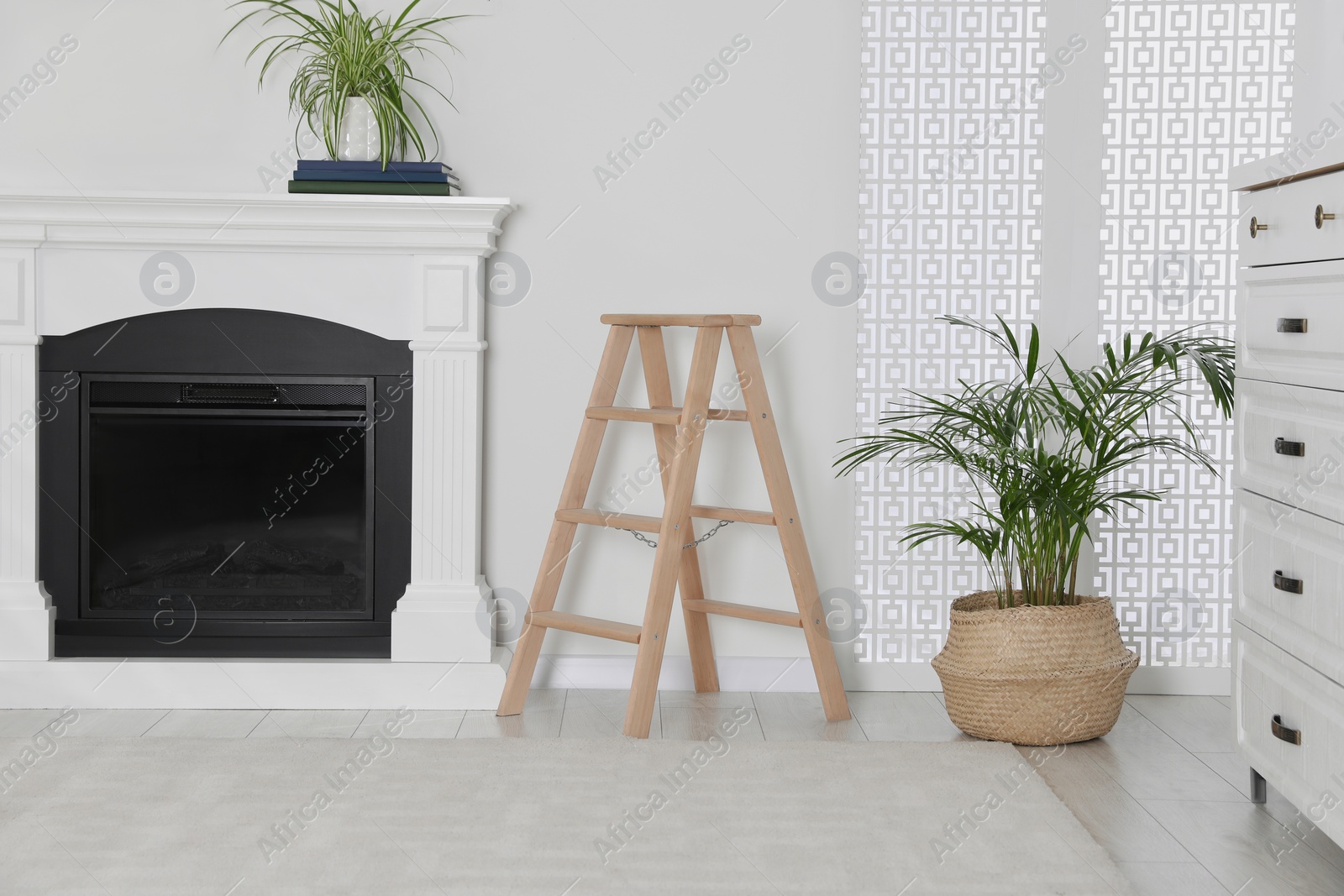 Photo of Wooden folding ladder near fireplace in stylish room