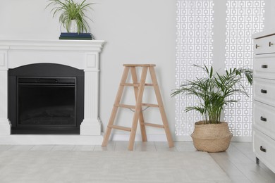 Photo of Wooden folding ladder near fireplace in stylish room