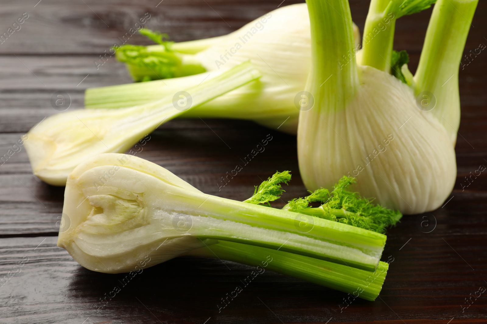 Photo of Whole and cut fennel bulbs on wooden table, closeup