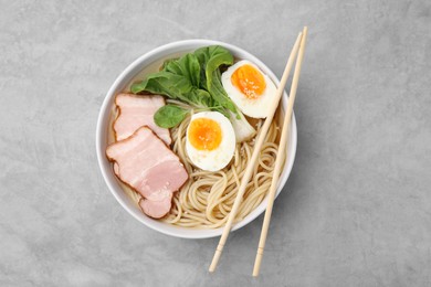 Photo of Delicious ramen with meat on light grey table, top view. Noodle soup