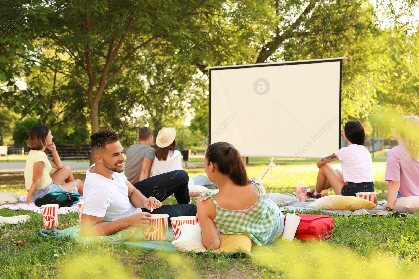 Photo of Young people with popcorn watching movie in open air cinema. Space for text