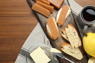 Photo of Delicious quince paste, bread, butter, cup of tea and fresh fruits on wooden table, flat lay. Space for text