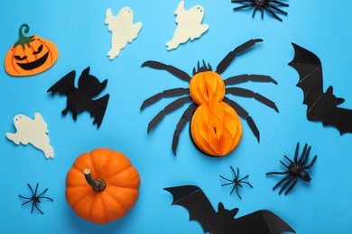 Flat lay composition with bats, pumpkins, ghosts and spiders on light blue background. Halloween celebration