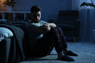 Photo of Frustrated man suffering from insomnia in bedroom at night