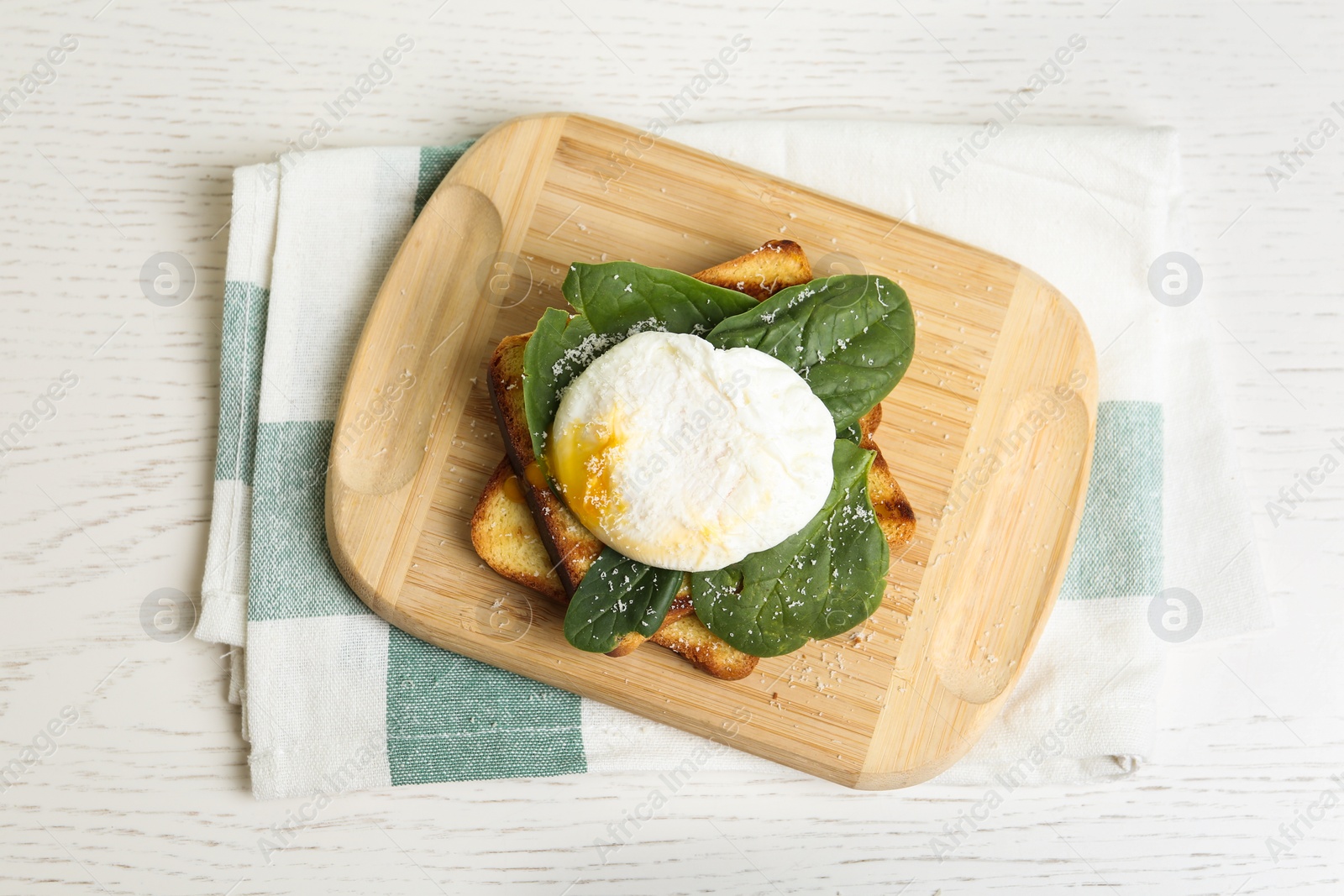 Photo of Delicious poached egg with toasted bread and spinach served on white wooden table, flat lay
