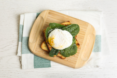 Photo of Delicious poached egg with toasted bread and spinach served on white wooden table, flat lay