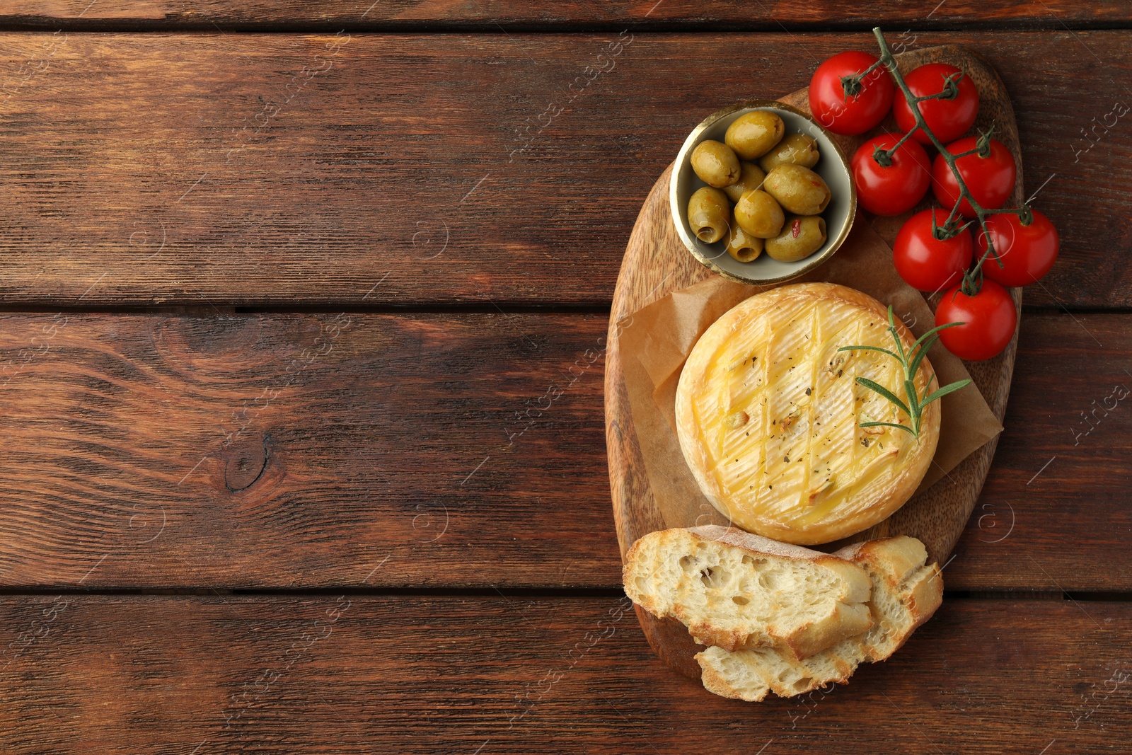 Photo of Tasty baked brie cheese served on wooden table, top view. Space for text