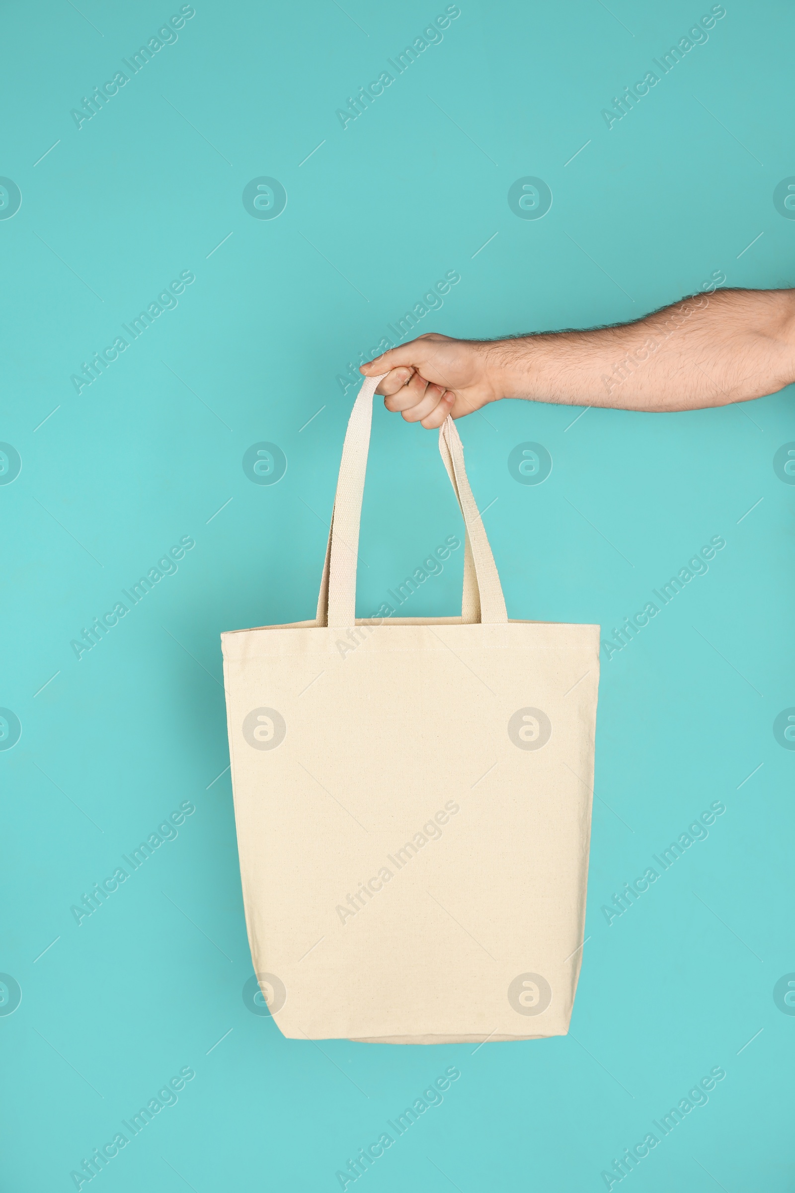 Photo of Man holding cotton shopping eco bag on color background. Mockup for design