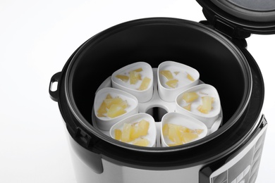 Photo of Cups of pineapple yogurt in multi cooker on white background, closeup