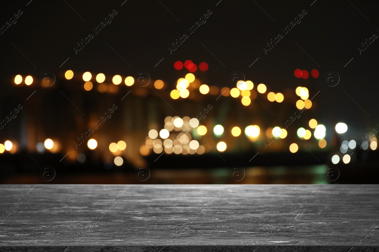 Image of Empty grey stone surface and blurred view of night city. Bokeh effect 