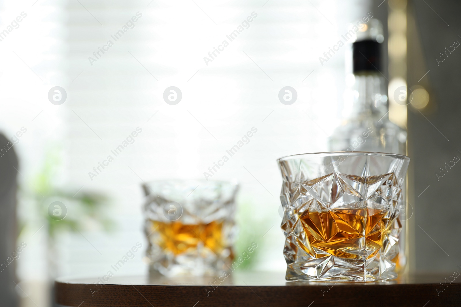 Photo of Glasses and bottle of whiskey on table indoors. Space for text