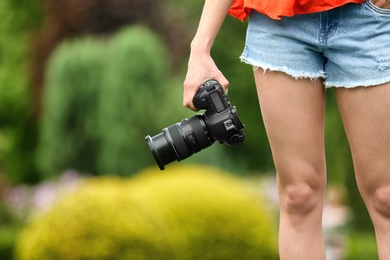 Photo of Photographer with professional camera in park, closeup. Space for text