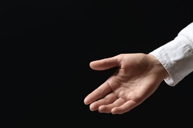 Photo of Woman holding something in hand on black background, closeup. Space for text