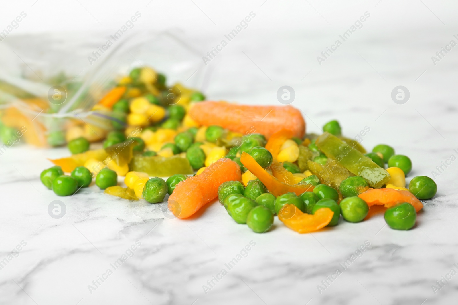 Photo of Mix of frozen vegetables on marble table, closeup