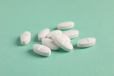 Photo of Pile of white pills on green background, closeup