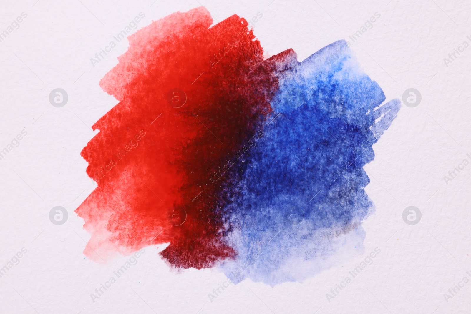 Photo of Blots of bright watercolor paints on white paper, top view