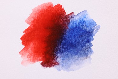 Photo of Blots of bright watercolor paints on white paper, top view