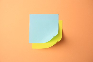 Blank paper notes on pale orange background, top view