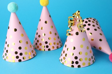 Photo of Pink party hats and serpentine streamers on light blue background