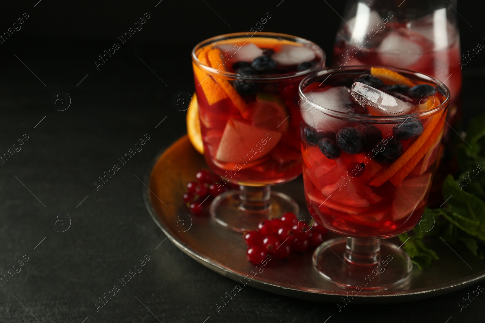 Photo of Delicious Red Sangria and ingredients on black table, space for text