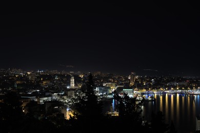 SPLIT, CROATIA - OCTOBER 08, 2023: Beautiful view of illuminated city with port and buildings at night