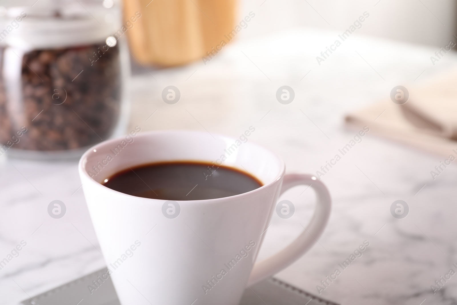 Photo of Delicious coffee in cup on white marble table, closeup. Space for text