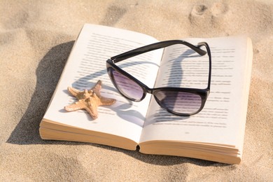 Photo of Beautiful sunglasses, book and starfish on sand