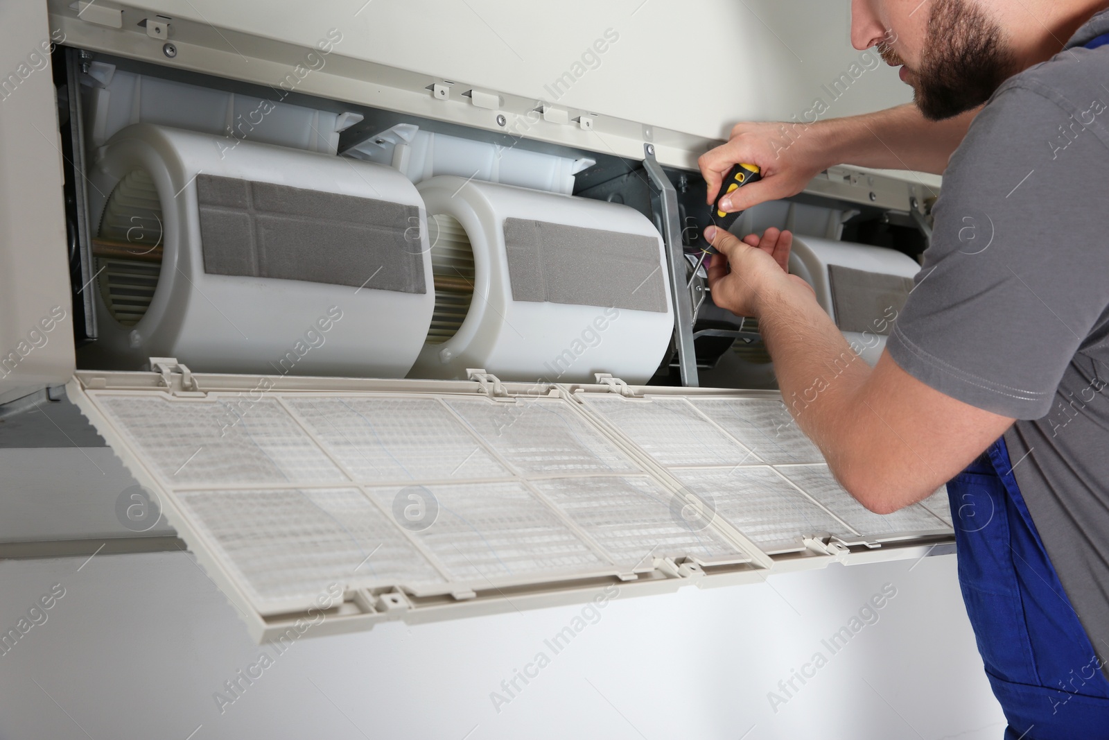 Photo of Young male technician repairing air conditioner indoors