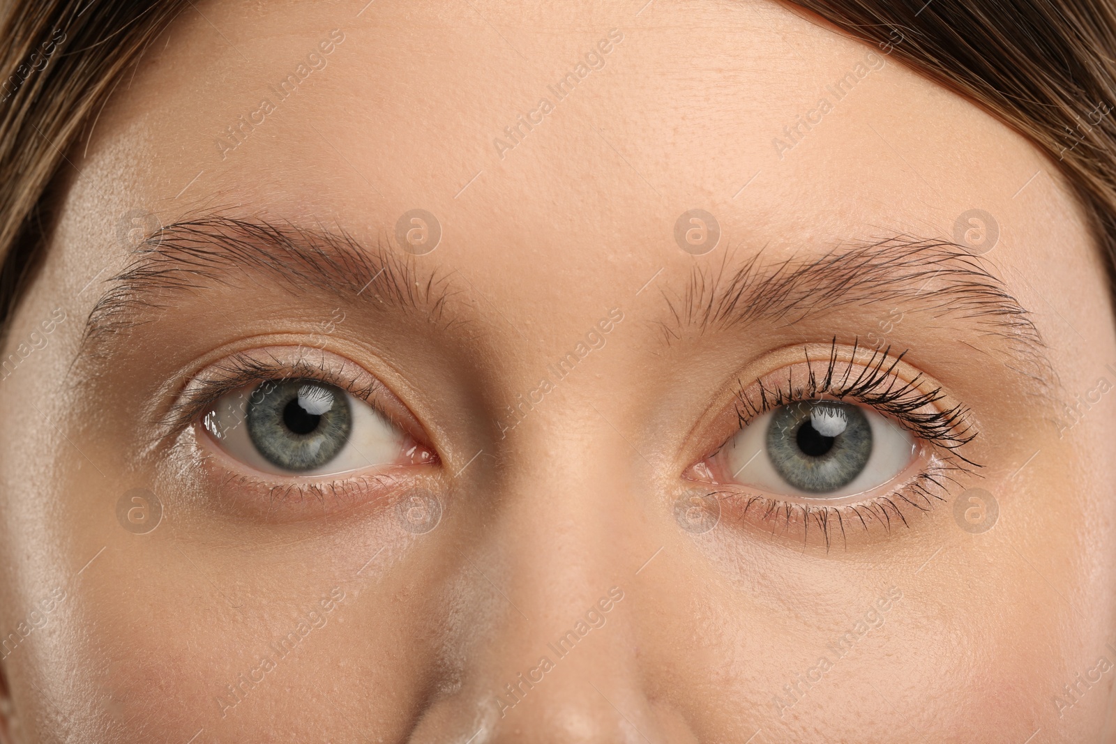 Photo of Woman showing difference in eyelashes length after mascara applying, closeup