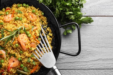 Photo of Tasty rice with shrimps and vegetables served on grey wooden table, flat lay. Space for text