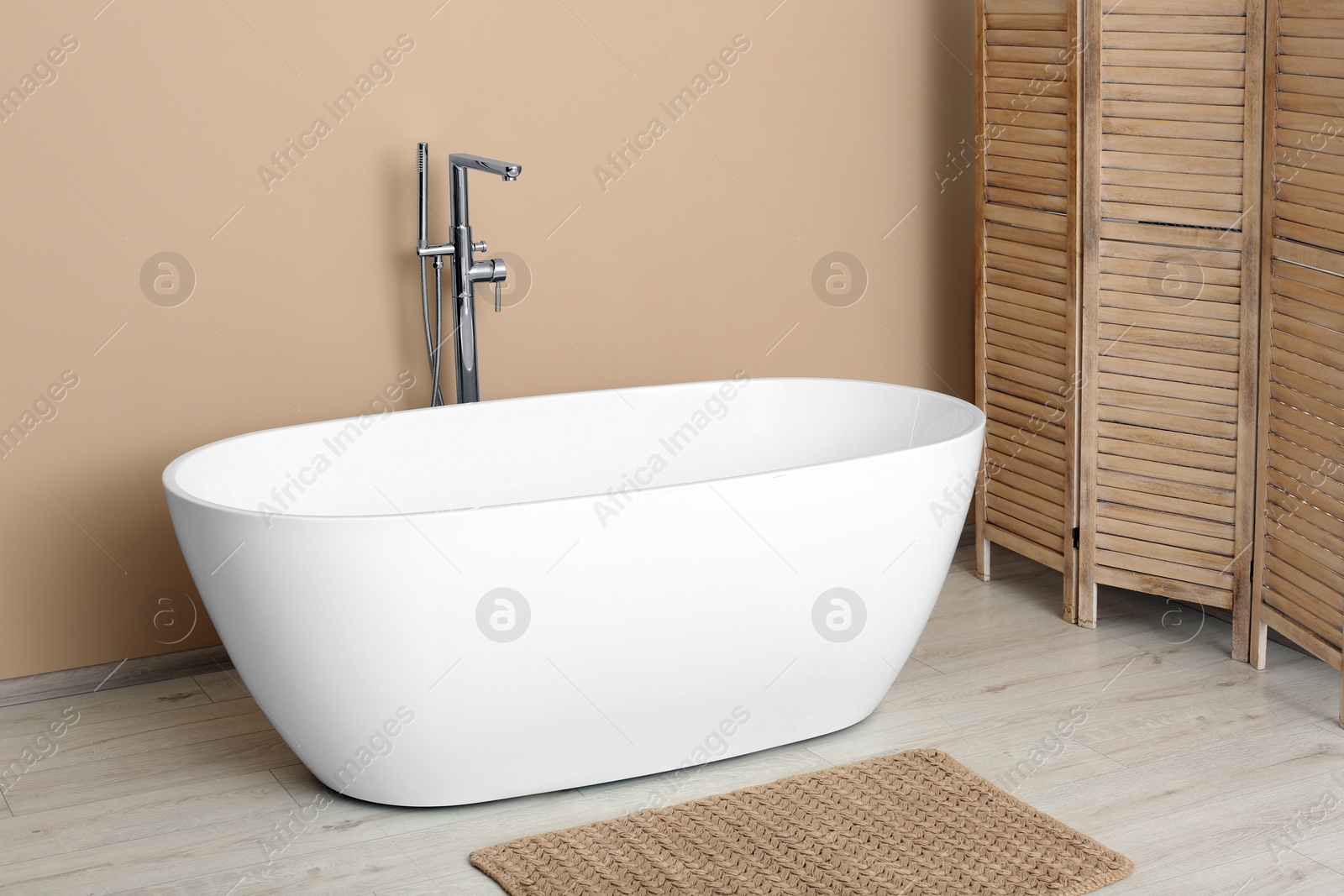 Photo of Beautiful white tub near beige wall in bathroom. Interior design