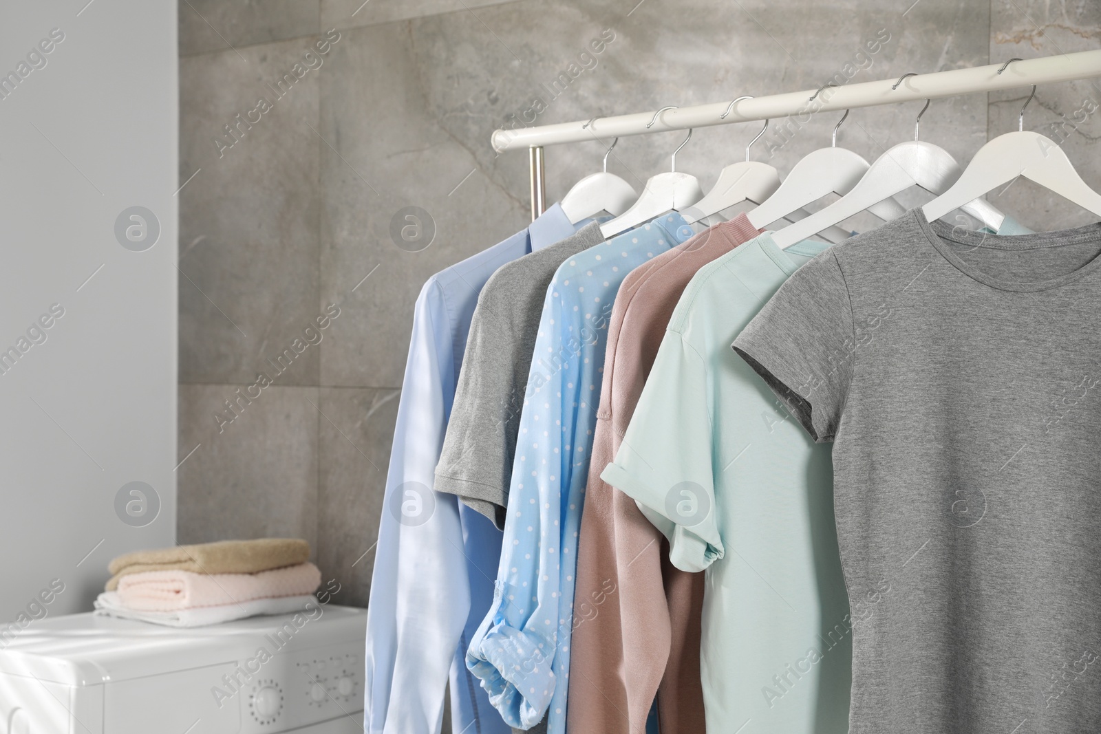 Photo of Different apparel hanging on clothes rack indoors, space for text